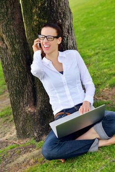 happy young student woman with laptop in city park study