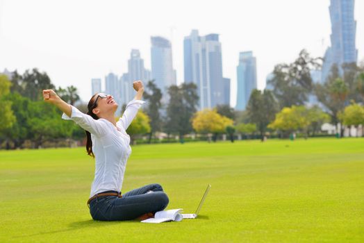 happy young student woman with laptop in city park study