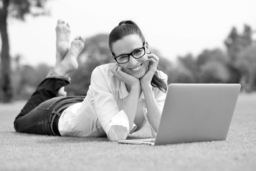 happy young student woman with laptop in city park study