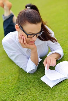 Young student woman reading a book and study in the park