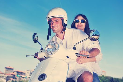 Portrait of happy young love couple on scooter enjoying themselves in a park at summer time