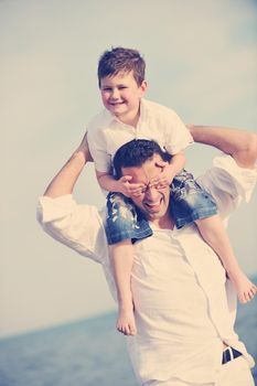 happy young  father and son have fun and enjoy time on beach at sunset and representing healthy family and support concept