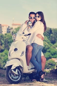 Portrait of happy young love couple on scooter enjoying themselves in a park at summer time