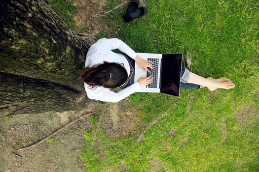 happy young student woman with laptop in city park study