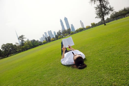 Young student woman reading a book and study in the park