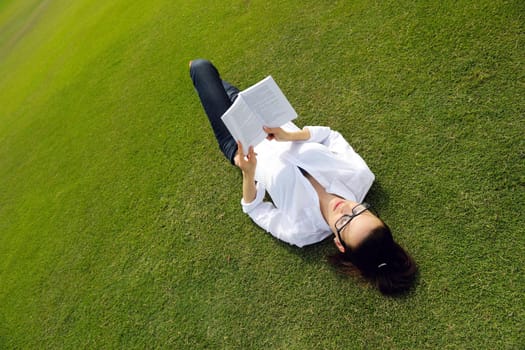 Young student woman reading a book and study in the park