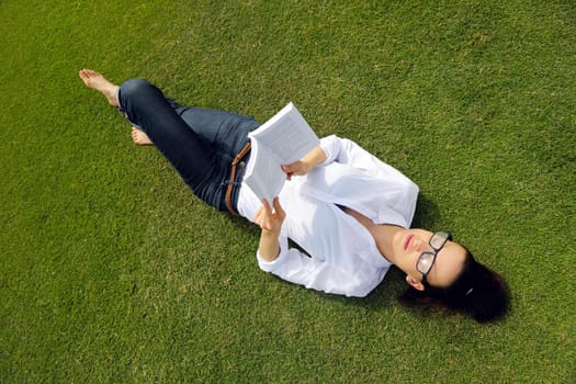 Young student woman reading a book and study in the park