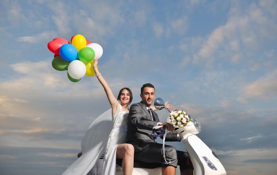 wedding sce of bride and groom just married couple on the beach ride white scooter and have fun