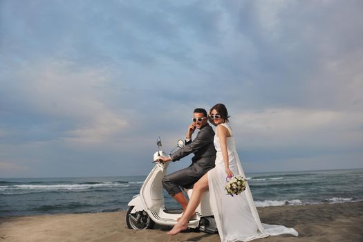 wedding sce of bride and groom just married couple on the beach ride white scooter and have fun