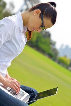 happy young student woman with laptop in city park study