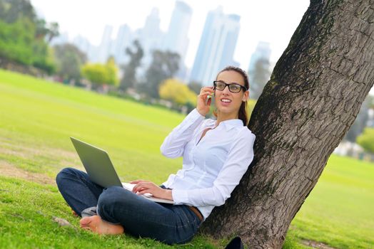 happy young student woman with laptop in city park study