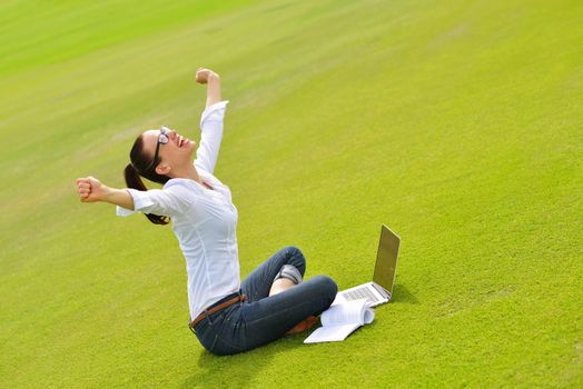 happy young student woman with laptop in city park study