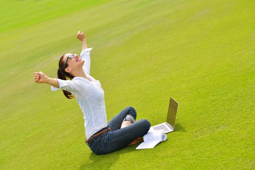 happy young student woman with laptop in city park study