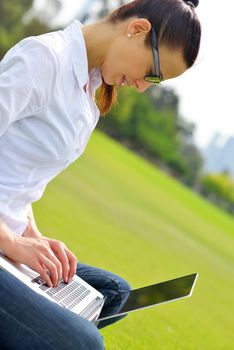 happy young student woman with laptop in city park study