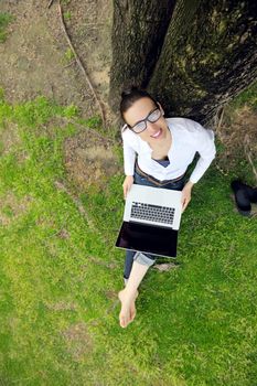 happy young student woman with laptop in city park study