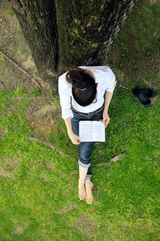 Young student woman reading a book and study in the park