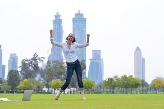 happy young student woman with laptop in city park study