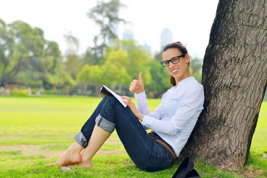 Young student woman reading a book and study in the park