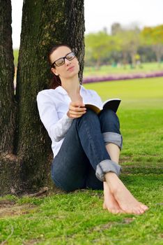 Young student woman reading a book and study in the park