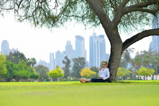 happy young student woman with laptop in city park study