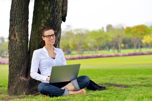 happy young student woman with laptop in city park study