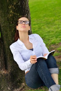 Young student woman reading a book and study in the park