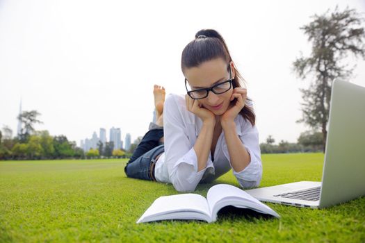 happy young student woman with laptop in city park study