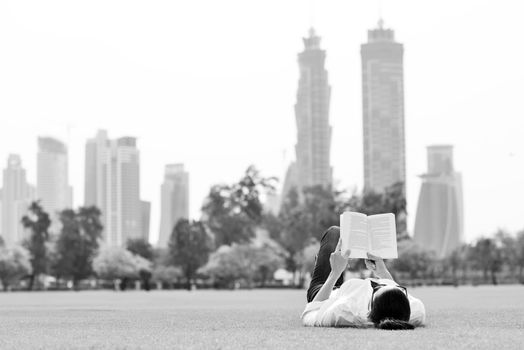 Young student woman reading a book and study in the park