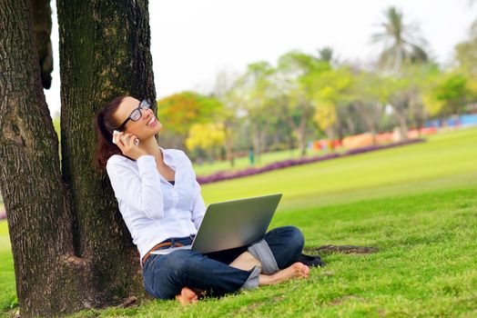 happy young student woman with laptop in city park study