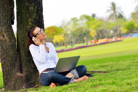 happy young student woman with laptop in city park study