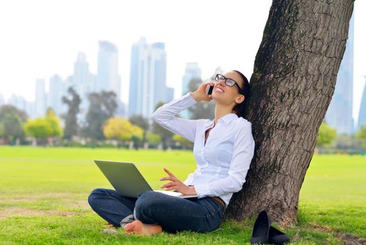 happy young student woman with laptop in city park study