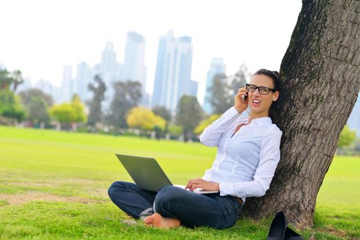 happy young student woman with laptop in city park study