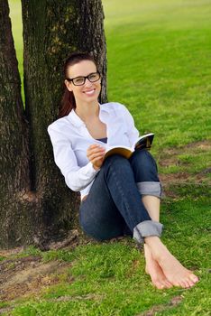 Young student woman reading a book and study in the park