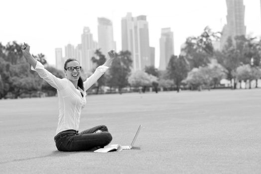 happy young student woman with laptop in city park study