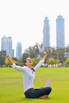 happy young student woman with laptop in city park study