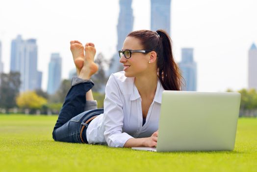 happy young student woman with laptop in city park study