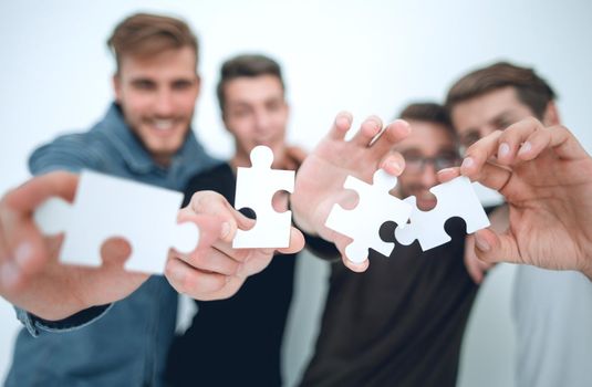 group of young people with puzzle pieces.the concept of solving the problem