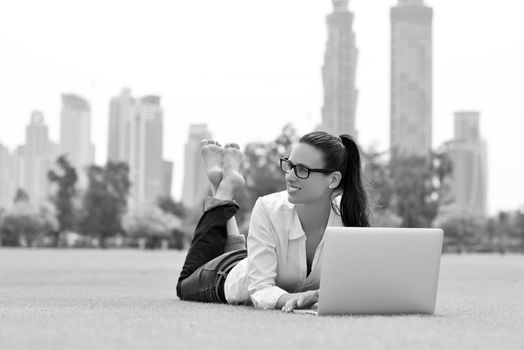 happy young student woman with laptop in city park study