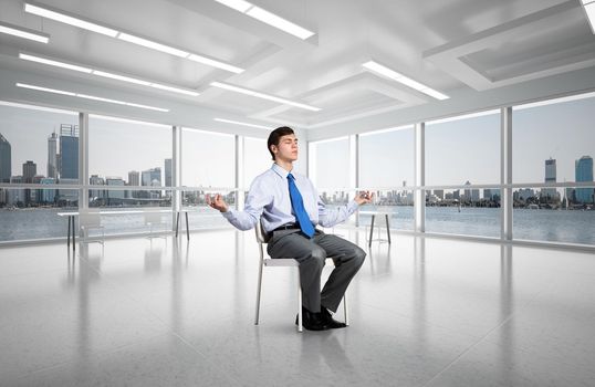 young businessman in the office meditates, achieve calmness, to achieve the goal