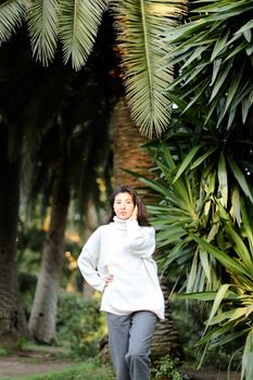 Japanese girl walking in tropical park and standing near palms. Concept asian beauty and nature.