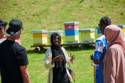 black african muslim woman giving presentation to group of business investors or tourists on small local  honey production farm