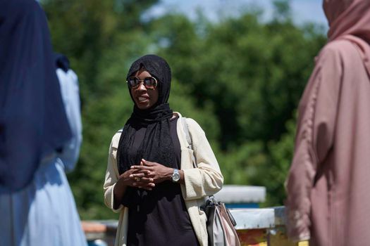 black african muslim woman giving presentation to group of business investors or tourists on small local  honey production farm