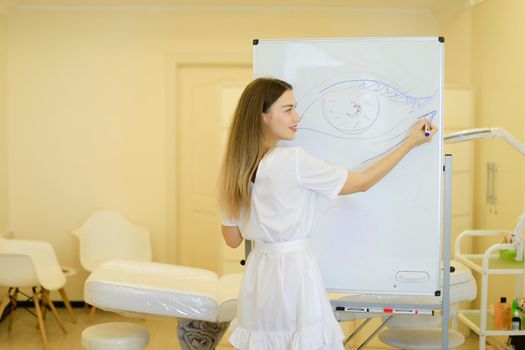 Cosmetologist draws eye on placard at cosmetology cabinet. Concept of permanent makeup courses and beauty salon.