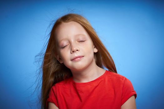 cheerful cute red-haired girl childhood blue background. High quality photo
