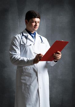 Doctor with tablet for documents, scans documents against the background of the wall