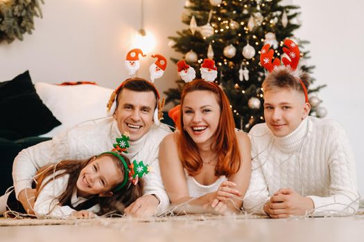 Close-up portrait of a happy family lying near a Christmas tree celebrating a holiday.