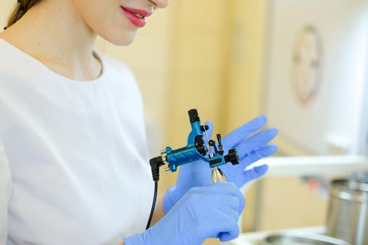 Close up cosmetlogist hands in latex gloves keeping microblading machine at beauty salon. Concept of permanent makeup artist and cosmetology equipment.