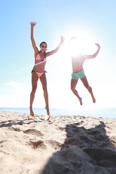 Picture of happy couple jumping on the beach.