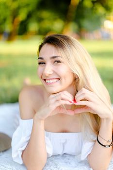 Young caucasian girl with red nails lying in park on plaid. Concept of having free time, picnic and summer vacations.