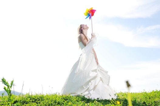 happy young beautiful bride after wedding ceremony event have fun outdoor on meadow at sunset with windmill toy and representing smart energy 